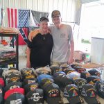 Jerry and Dolores Colwart at Booth 230 - August 2025 Vendor of the Month at Lafayette Jockey Lot, featuring military caps, sports jerseys, and jewelry