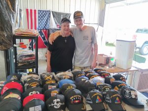 Jerry and Dolores Colwart at Booth 230 - August 2025 Vendor of the Month at Lafayette Jockey Lot, featuring military caps, sports jerseys, and jewelry