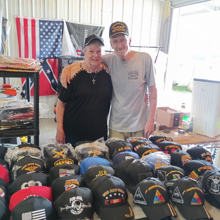 Jerry and Dolores Colwart at Booth 230 - August 2025 Vendor of the Month at Lafayette Jockey Lot, featuring military caps, sports jerseys, and jewelry